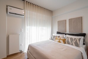 A bedroom with a bed, a radiator, and a window with curtains.