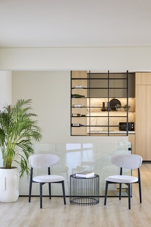 A modern living room with two chairs, a glass table, a potted plant, and a built-in bookshelf. - Acropolis Terraces in Athens (Athens)