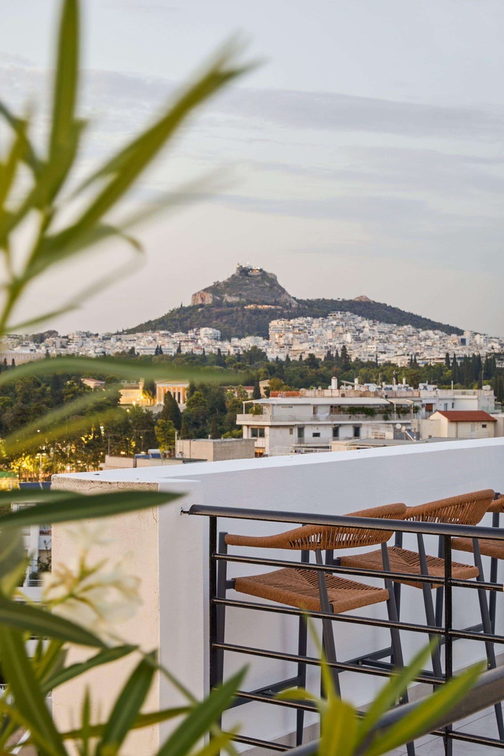 Uma varanda com vista para um horizonte urbano e uma colina com um edifício no topo.