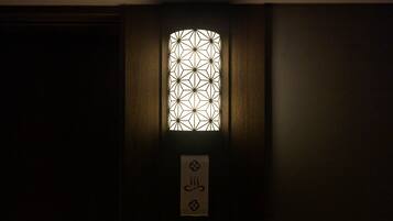 Una puerta de madera oscura con un ventanal de diseño geométrico y un letrero con un símbolo.