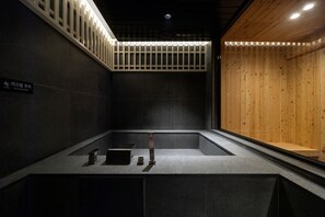 A modern bathroom with a dark tile wall, a wooden partition, and a sink with a mirror. - Sowon Ryokan and Hotel by Anook Sangbong (Seoul)