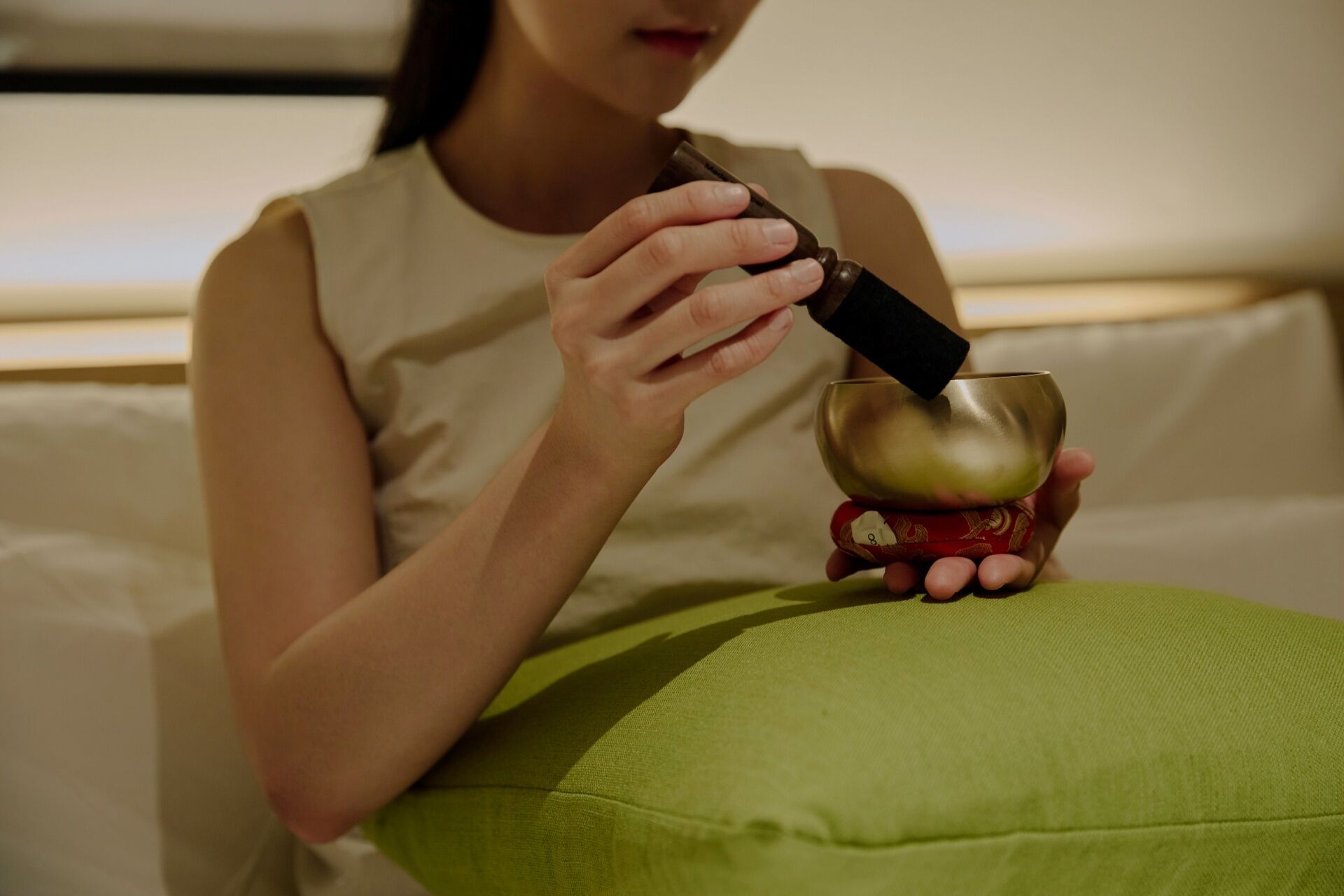 Une personne assise sur un coussin vert, tenant un téléphone intelligent et un verre.