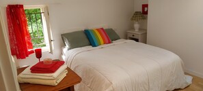 A bedroom with a bed, a nightstand with a lamp, a window with curtains, and a table with towels. - Guest Room “La Lagune” with Shared Terrace, Private Garden and Wi-Fi (Saint-André-de-Cubzac)