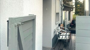 A narrow outdoor corridor with a metal gate, a small step leading to a porch, and a metal chair. - Apartment in Trier With Parking (Trier)