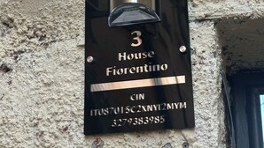 Een huisnummerbord met een plaquette waarop 'House Fiorentino' en een CIN-code staan.