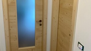 A wooden door with a frosted glass panel and a door handle. - New apartment in Val di Sole, close to ski slopes and bike trails (Trentino-Alto Adige)