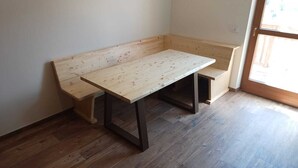 A corner room with a wooden bench and a table. - New apartment in Val di Sole, close to ski slopes and bike trails (Trentino-Alto Adige)