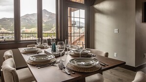 Mesa de comedor para seis personas con vista a las montañas a través de amplios ventanales.