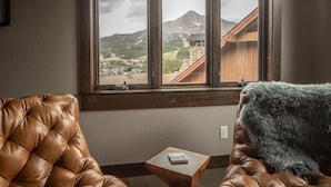 Una habitación con dos sillones de cuero orientados hacia una ventana que ofrece vistas a una montaña y un edificio de madera.