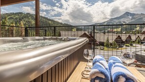 Un jacuzzi con terraza de madera y vistas a un paisaje montañoso.