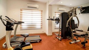 Een sportschool met een loopband, een hometrainer en krachttoestellen.