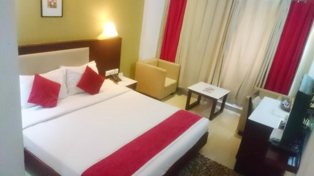 Une chambre d’hôtel avec un grand lit, une table de chevet, une chaise, une petite table et un téléviseur.