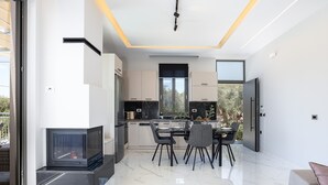 Een moderne keuken met een eethoek, grote ramen en een inbouwvuurplaats.