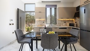 Een moderne keuken met een eethoek, met een marmeren aanrechtblad, inbouwapparatuur en uitzicht op het exterieur.