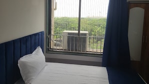 Une chambre d’hôtel avec un lit, une fenêtre donnant sur un espace verdoyant et une armoire.