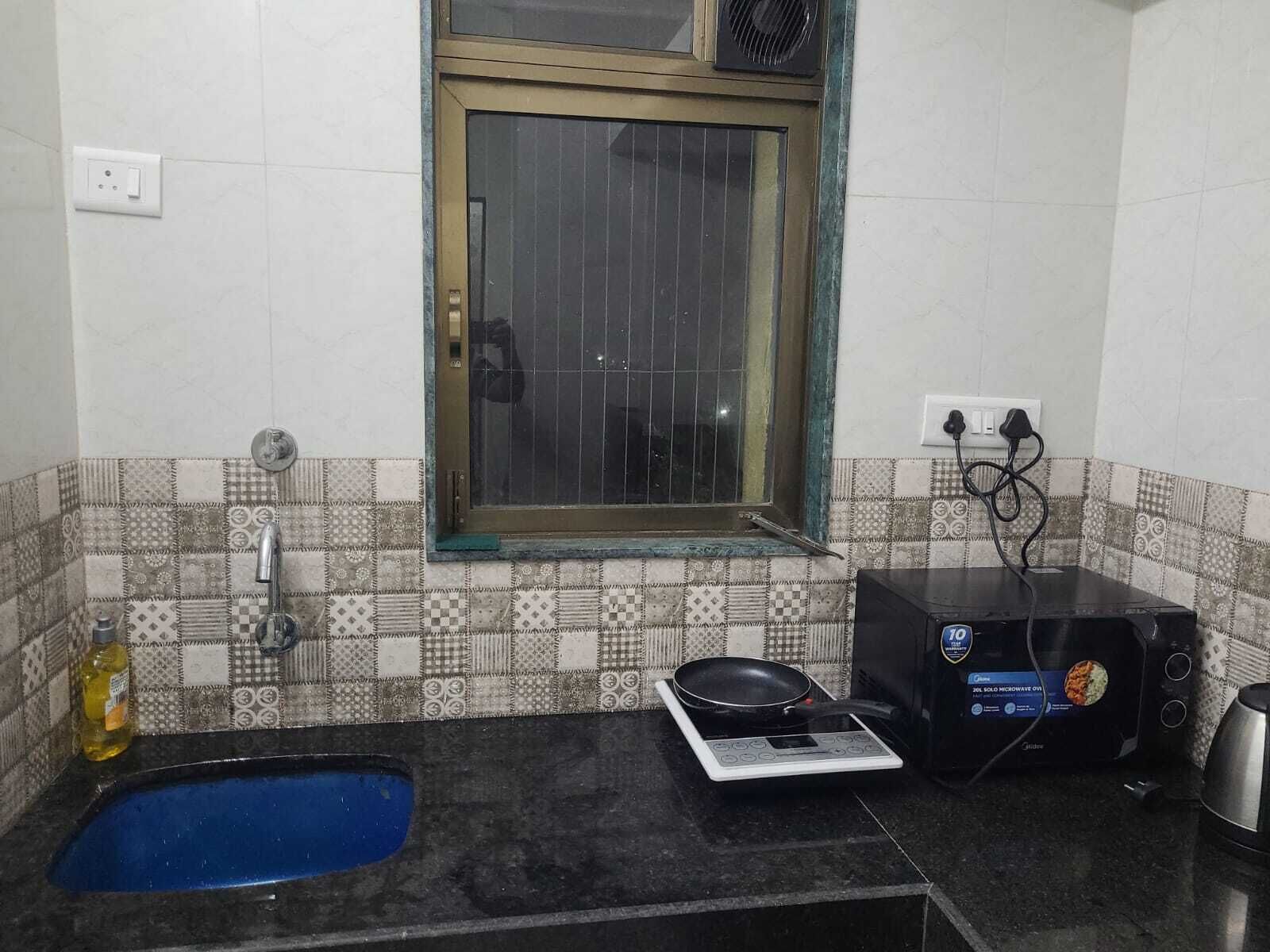 A small kitchen with a window, a sink, a stove, and a microwave.