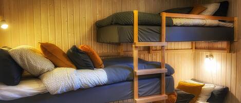 Ein Schlafzimmer mit Etagenbetten, Holzwänden und einer Leiter.