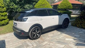 En hvid SUV parkeret på en brostensbelagt indkørsel.