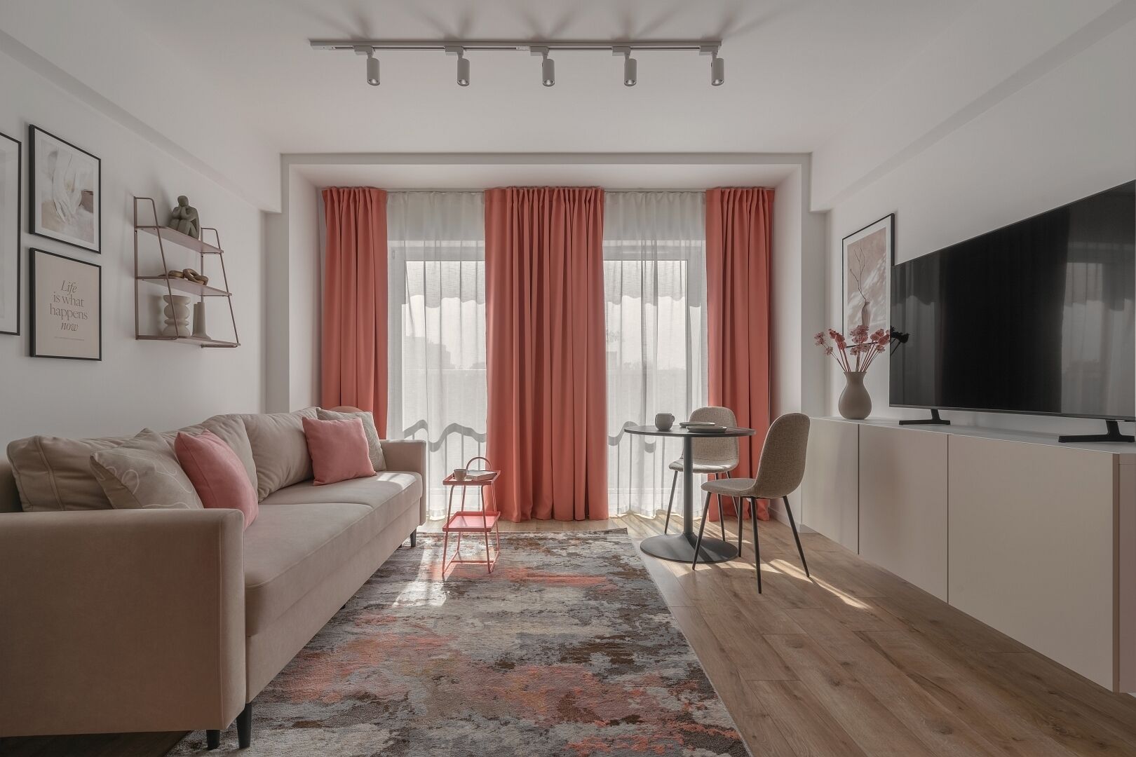 A modern living room with a sofa, a dining table with chairs, a TV, and a large window with curtains.