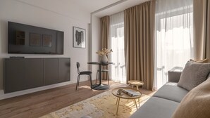 A modern living room with a sofa, a TV, a dining table, and a coffee table. - Apartio Rooms Zabrze (Zabrze)