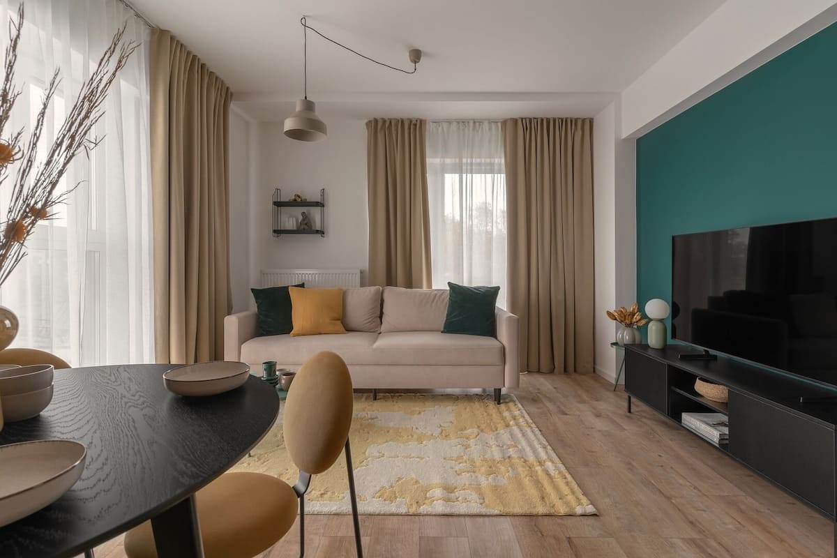 Een moderne woonkamer met een bank, televisie en eethoek.