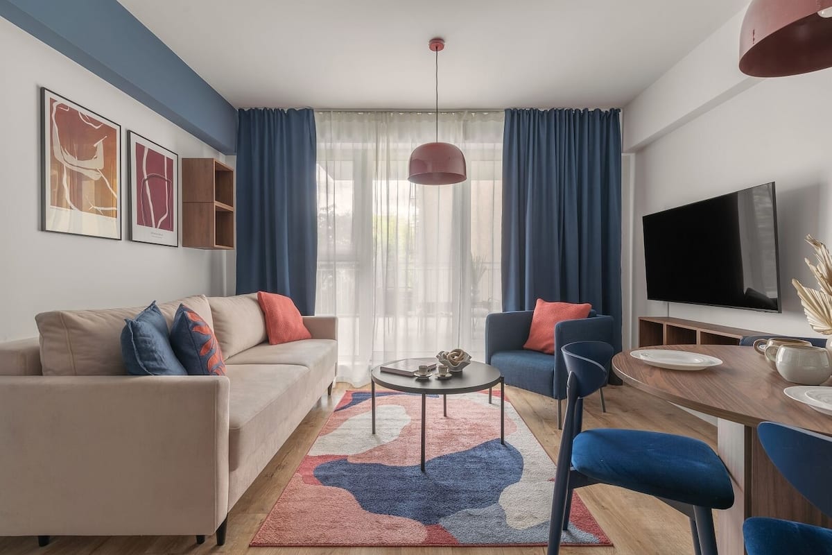 Een moderne woonkamer met een bank, stoelen, een salontafel en een televisie.
