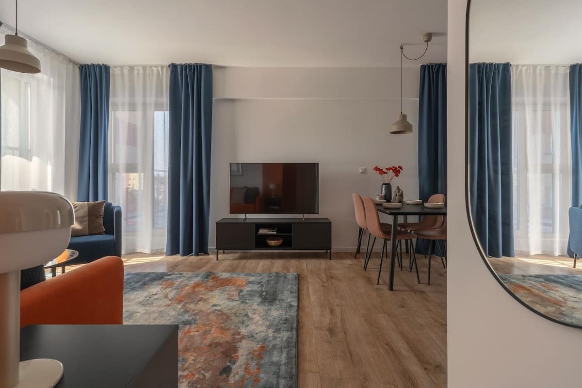 Een moderne woonkamer met een bank, televisie, eettafel en stoelen.