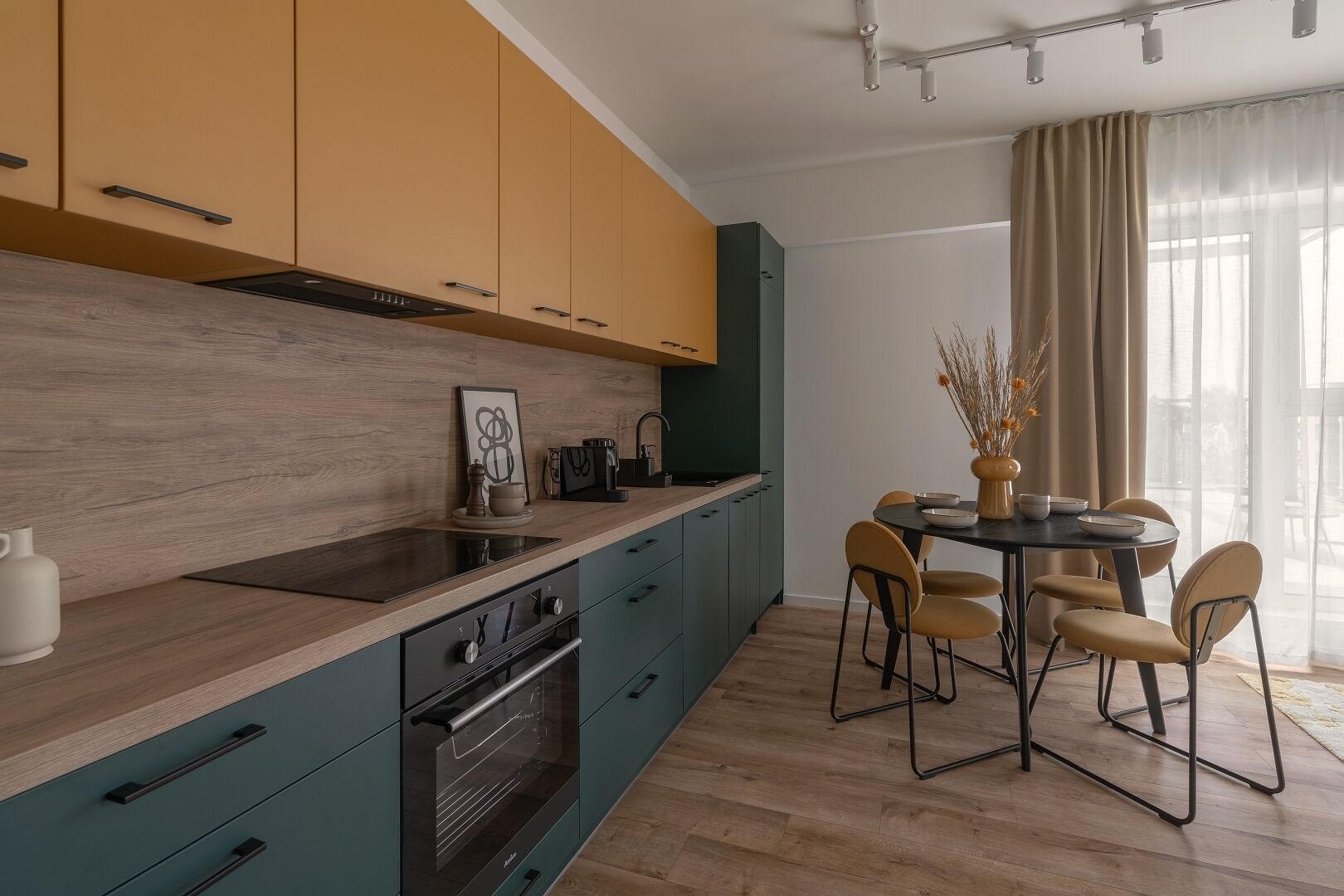 Una cucina moderna con mobili color acquamarina e giallo, un piano di lavoro in legno e un'area pranzo con un tavolo rotondo e sedie.