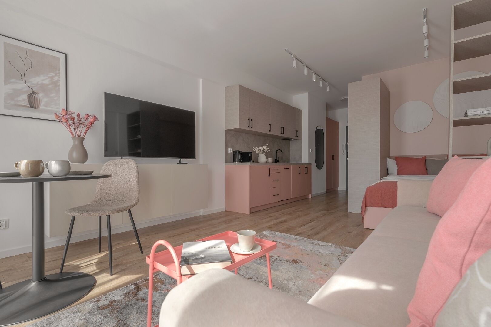 Un soggiorno moderno con un divano, un tavolino e una TV. C'è un angolo cottura con mobili rosa e un tavolo da pranzo con sedie.