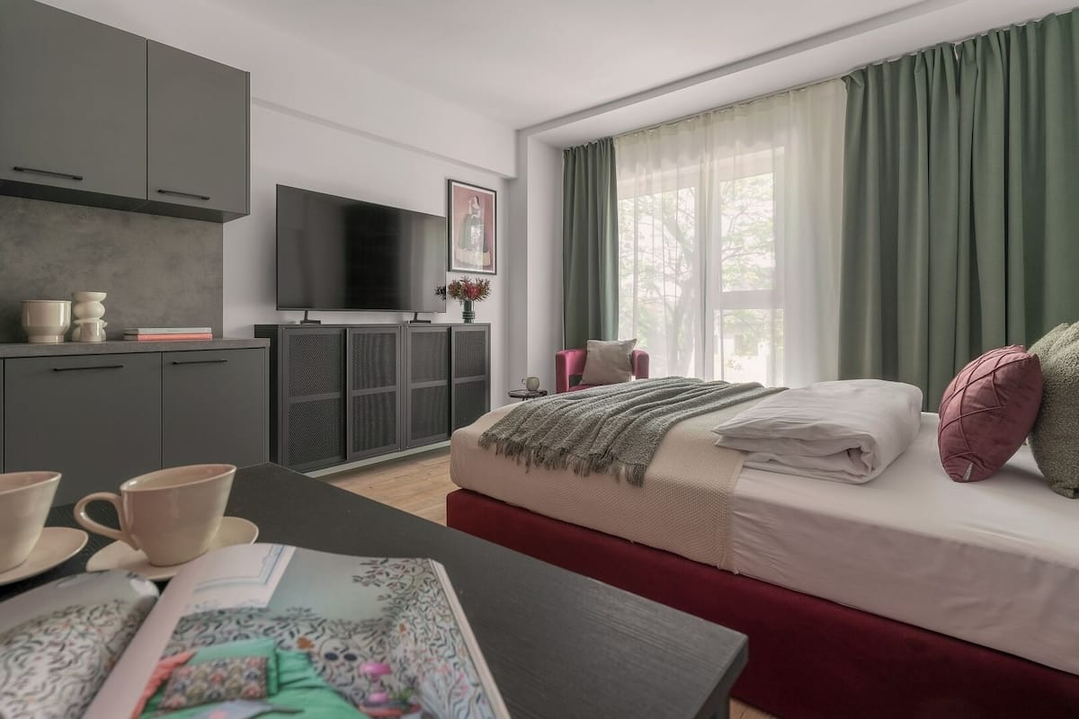 Een moderne slaapkamer met een bed, een televisie en een zithoek.
