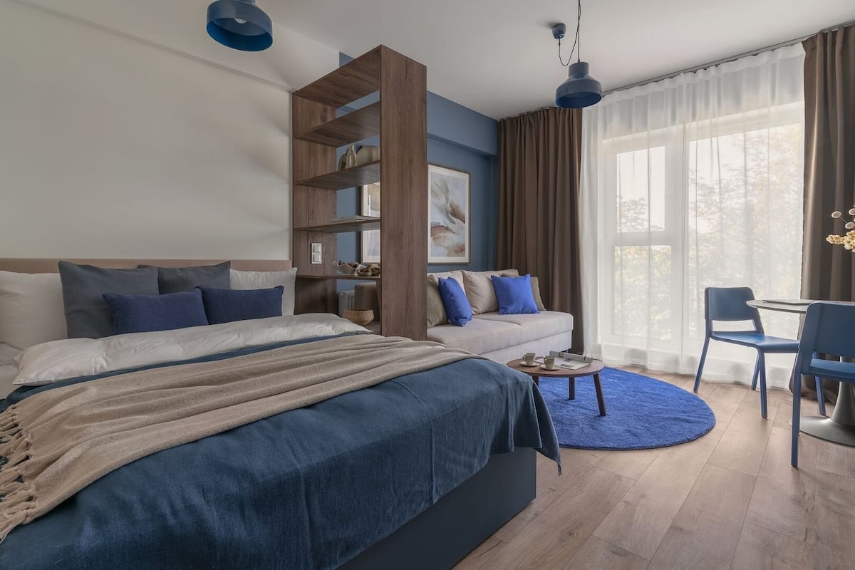Een moderne slaapkamer met een groot bed, een sofa, een bureau en een boekenkast.