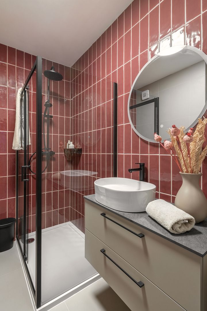 A modern bathroom with a glass-enclosed shower, a white sink, and a vanity with drawers.