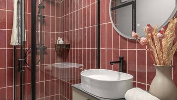 A modern bathroom with a glass-enclosed shower, a white sink, and a vanity with drawers.