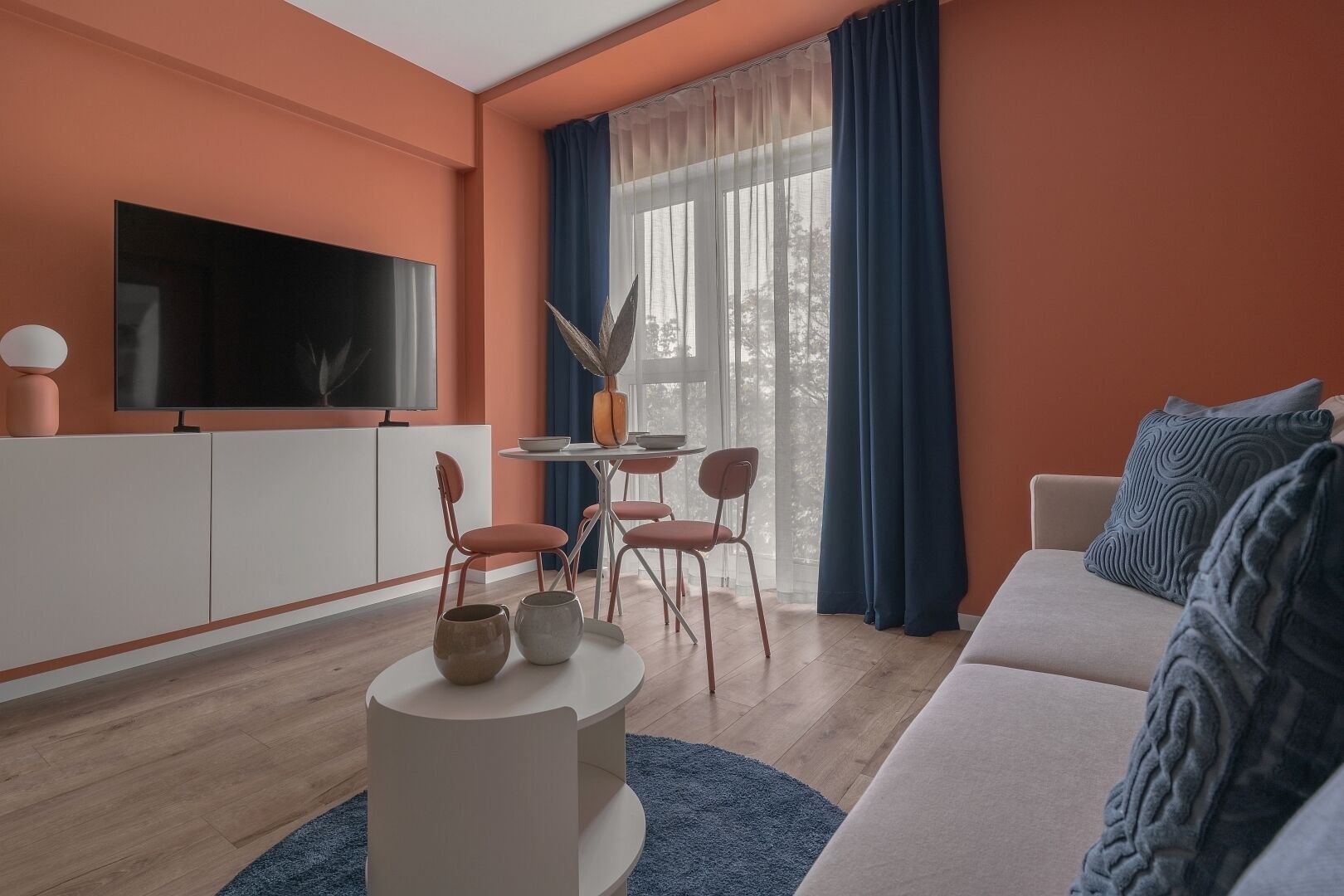 A modern living room with a TV, dining table, chairs, and a sofa.