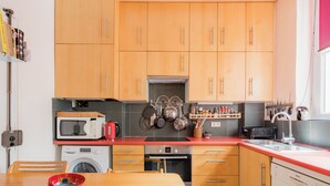Una cocina compacta con armarios de madera, microondas, cafetera y lavavajillas.