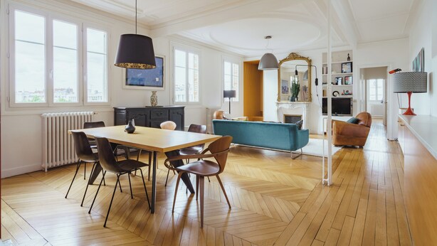 A spacious living area with a dining table, chairs, a sofa, and a TV.
