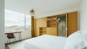 A modern bedroom with a large bed, a desk, and a wardrobe.