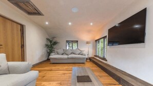 Ein modernes Wohnzimmer mit einer Couch, einem Couchtisch und einem an der Wand befestigten Fernseher.