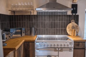 A kitchen with a stove, toaster, and a wooden cutting board. - The Coach House, Windermere (Windermere)