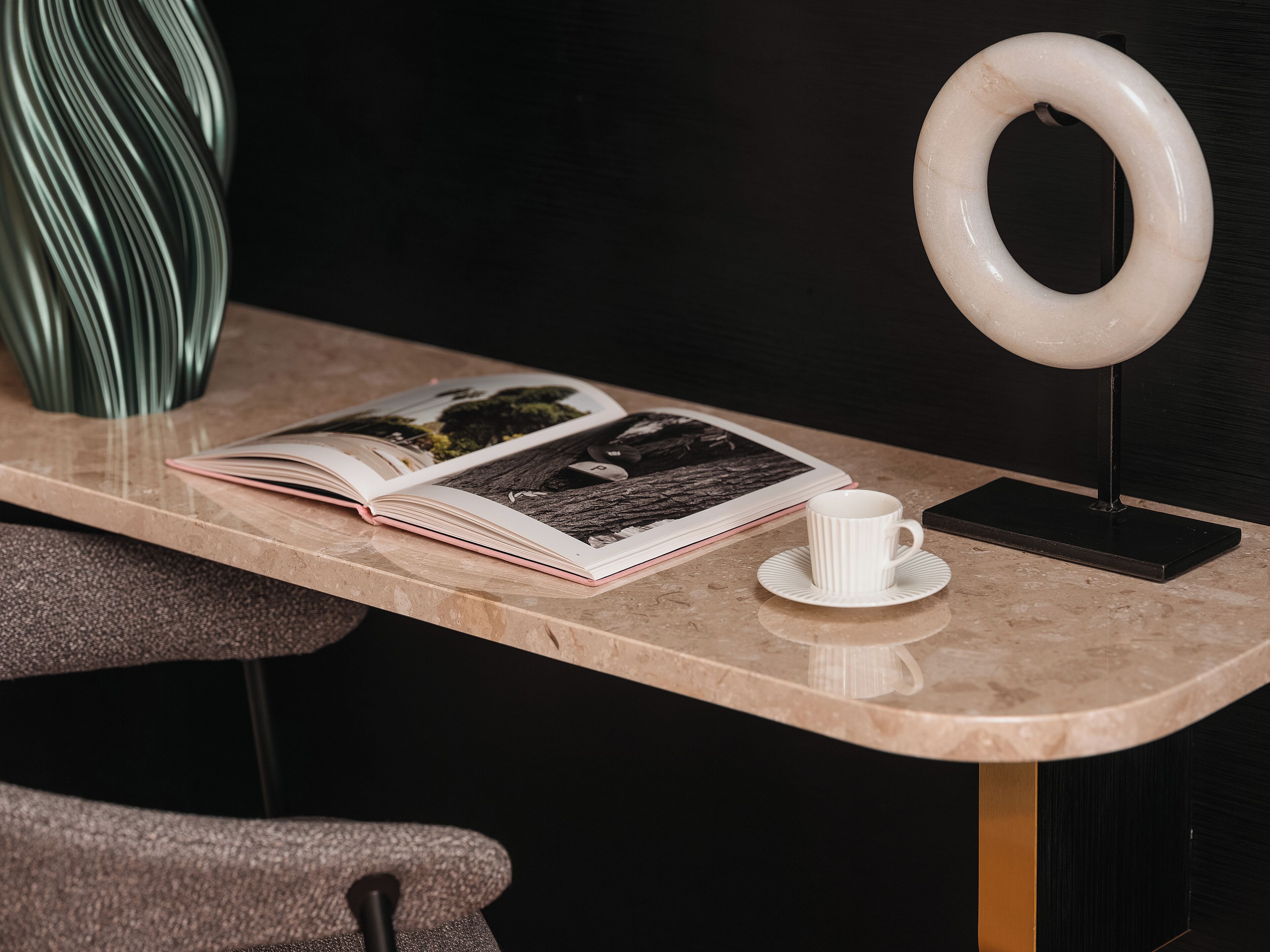A marble table with a book, a white cup, and a ring light.