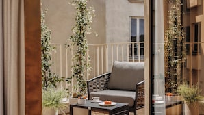 Un balcone con una sedia in vimini, un tavolino e piante in vaso.