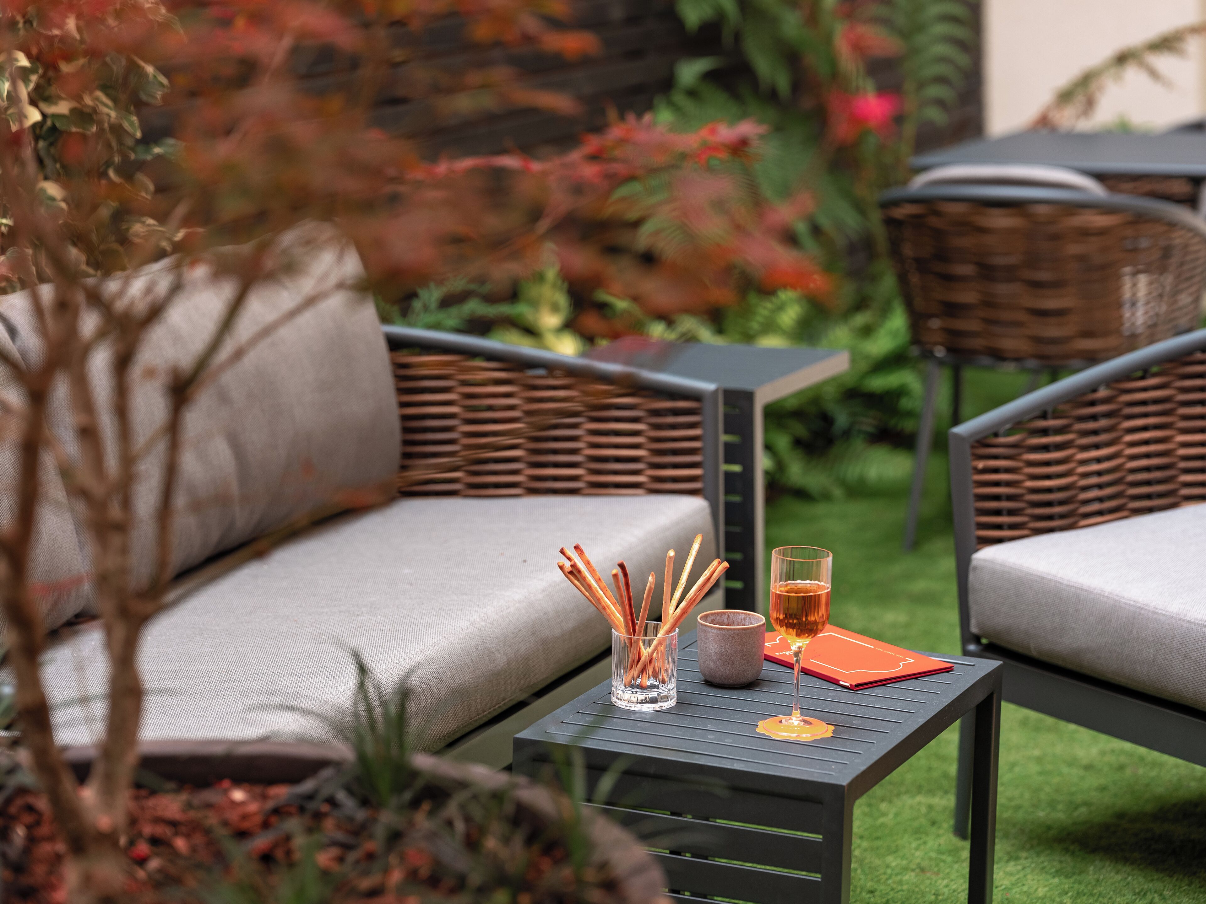 Un patio con mobiliario exterior, una mesa con una bebida y una vela, y una planta en maceta.
