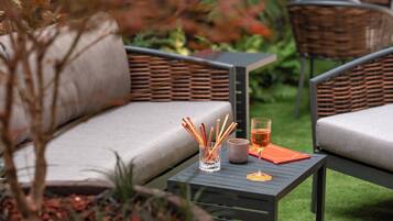 Un patio con mobiliario exterior, una mesa con una bebida y una vela, y una planta en maceta.