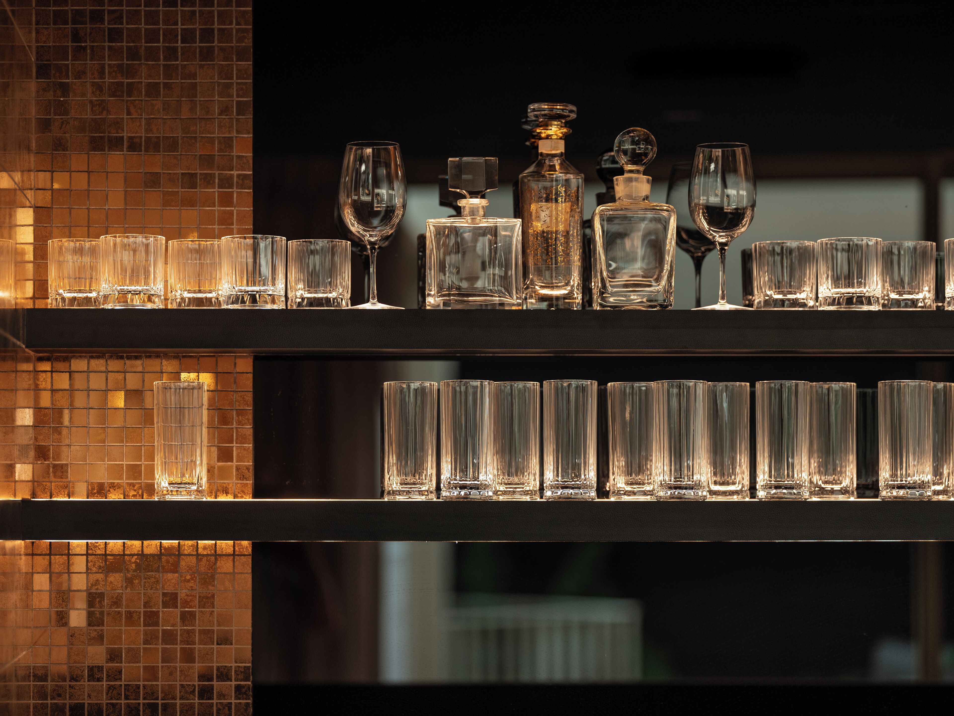 A bar area with multiple shelves of clear glassware and bottles.