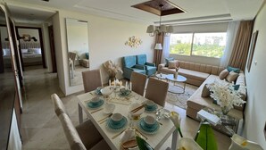 A modern living room with a dining area, a sofa set, and a large window offering a view of the outdoors. - steps from everything (Tangier)