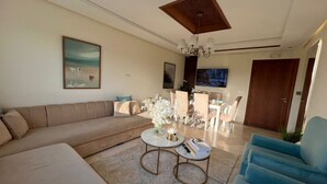 A modern living room with a beige sofa, a blue armchair, and a dining area with a chandelier. - steps from everything (Tangier)