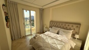 A bedroom with a large bed, a nightstand, a lamp, and a sliding glass door leading to a balcony. - steps from everything (Tangier)