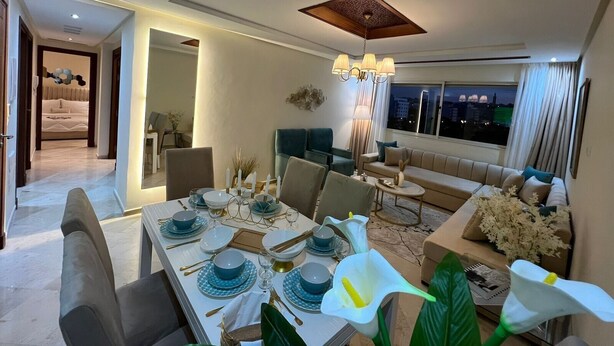 A modern dining area with a table set for four, a sofa, and a chandelier. - steps from everything (Tangier)