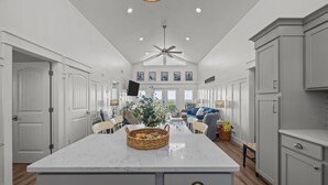 A spacious kitchen with a large island, white cabinetry, and a ceiling fan. - Waterfront Paradise in N. Topsail: Ocean/Canal Views, Fishing, Steps from Beach (North Topsail Beach)