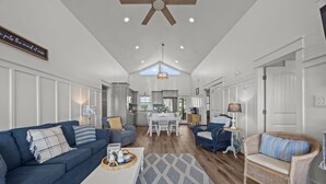 A spacious living area with a sofa, armchair, and coffee table. A dining table and chairs are visible in the background. - Waterfront Paradise in N. Topsail: Ocean/Canal Views, Fishing, Steps from Beach (North Topsail Beach)